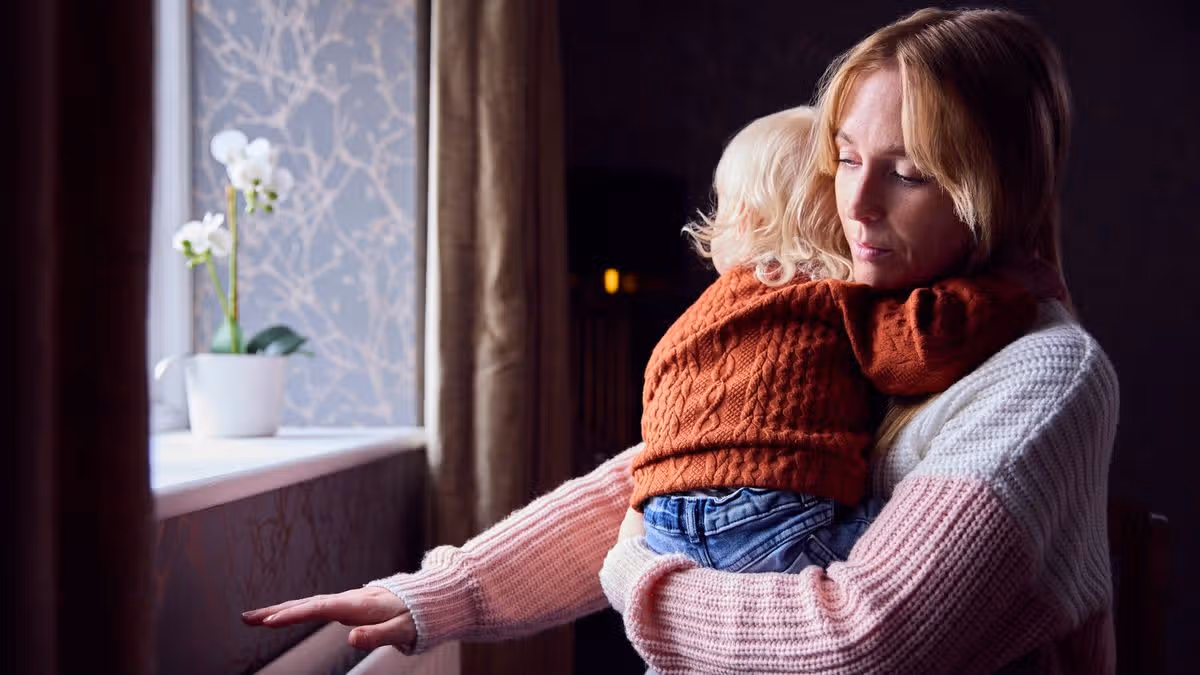 11_Mother-With-Son-Trying-To-Keep-Warm-By-Radiator-At-Home-During-Cost-Of-Living-Energy-Crisis.jpg